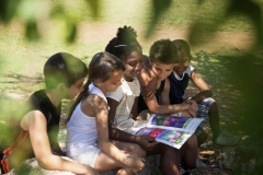 Young people and education, two little girls and boys reading book in city park